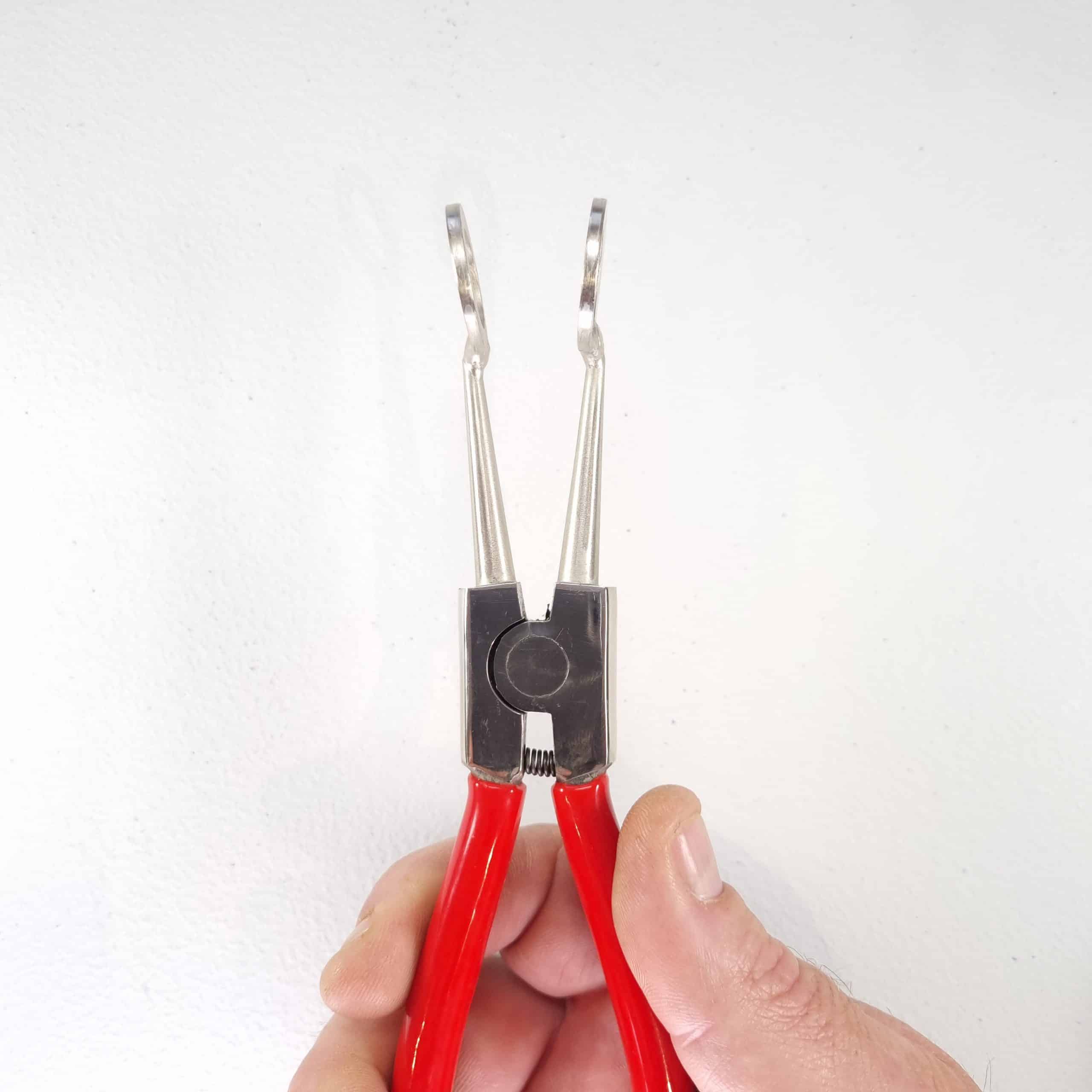 Hoof Spreaders — Cattle Claw Separation Tool 2 Hand holding the Hoof It cattle claw spreader by its red handles, showing the pointed prongs in use